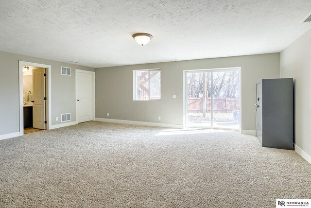 spare room featuring carpet floors, visible vents, and a textured ceiling