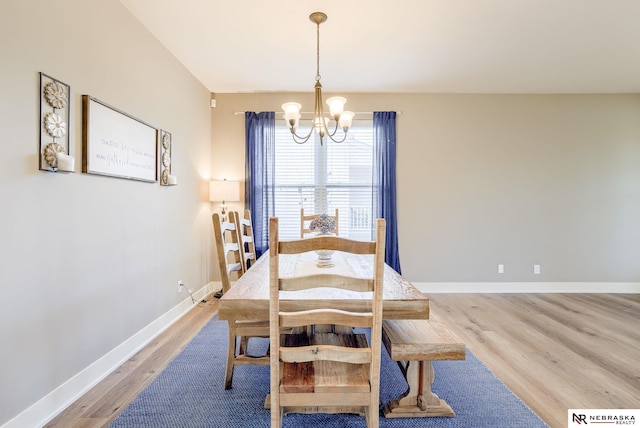 dining area with a chandelier, light wood-style flooring, and baseboards