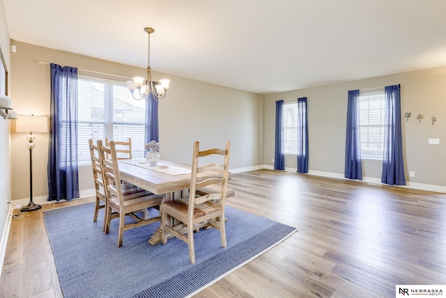 dining room featuring baseboards, plenty of natural light, wood finished floors, and an inviting chandelier