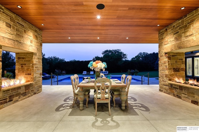 view of patio / terrace with outdoor dining area, an outdoor stone fireplace, and visible vents