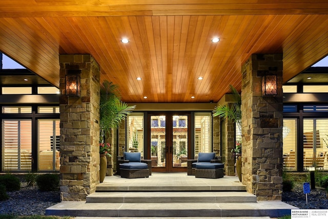 view of exterior entry featuring a porch, french doors, and stone siding