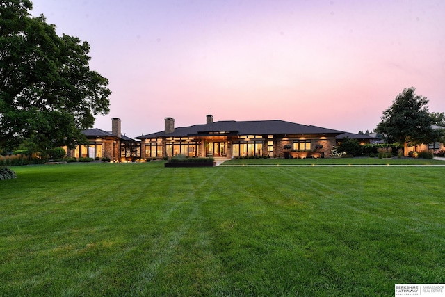 back of house at dusk with a yard