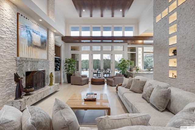 tiled living room with crown molding, a high ceiling, and a high end fireplace