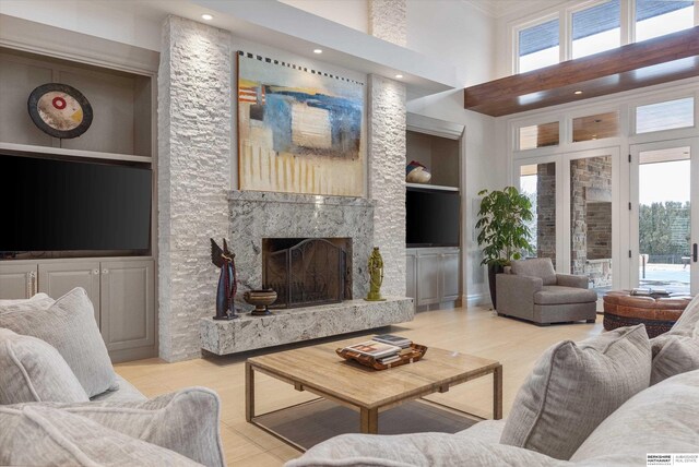 living room featuring built in features, a healthy amount of sunlight, a high end fireplace, and a towering ceiling