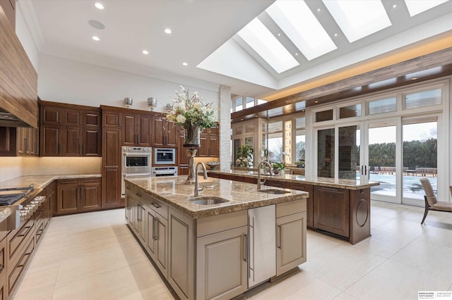 kitchen with a spacious island, ornamental molding, a skylight, and a sink