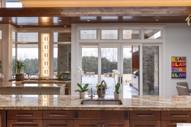 kitchen with a sink, light stone countertops, a healthy amount of sunlight, and recessed lighting