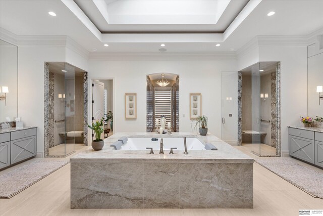 full bath with a raised ceiling, a bath, vanity, and ornamental molding