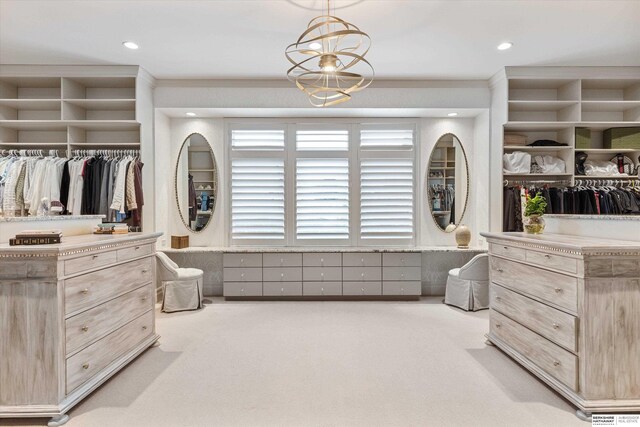 walk in closet featuring carpet and an inviting chandelier