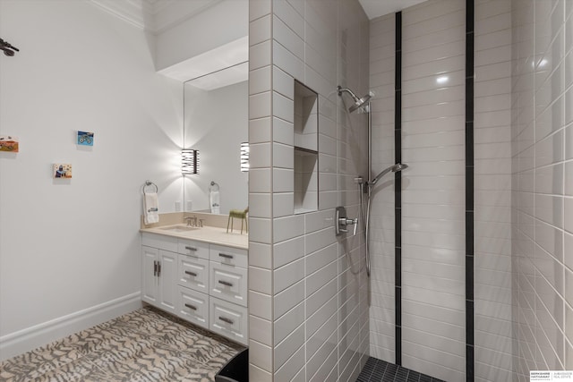 bathroom featuring tiled shower, vanity, and baseboards