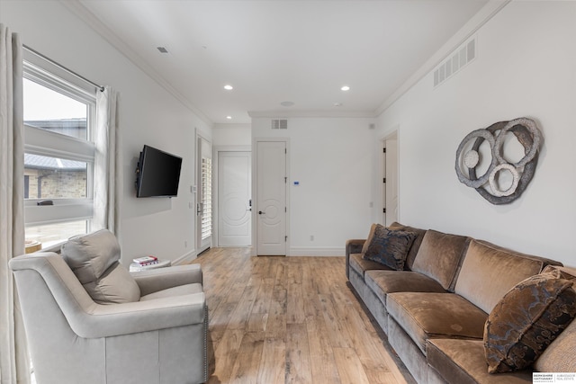 living area featuring visible vents, baseboards, crown molding, and light wood-style floors