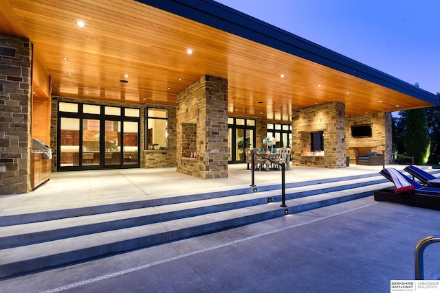 view of patio / terrace with french doors and an outdoor stone fireplace