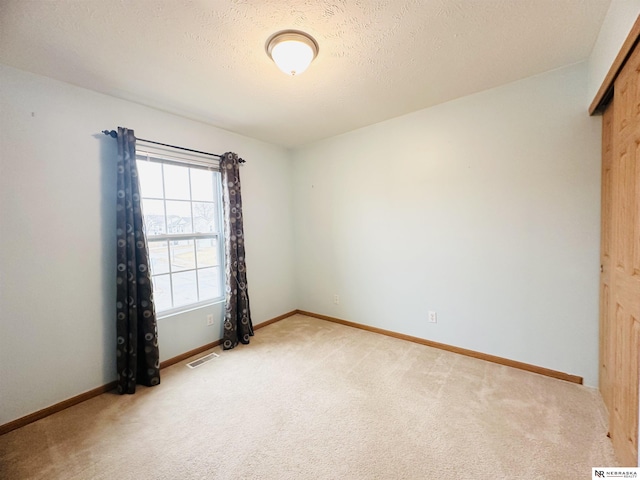 spare room with visible vents, light carpet, and baseboards