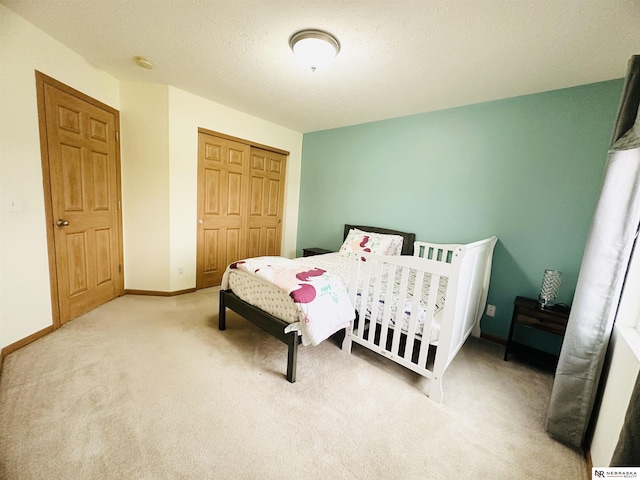 carpeted bedroom with baseboards, a closet, and a textured ceiling