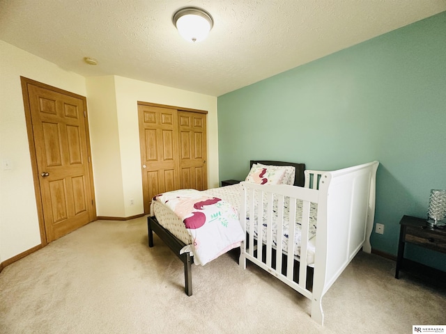 bedroom with a closet, baseboards, a textured ceiling, and carpet floors