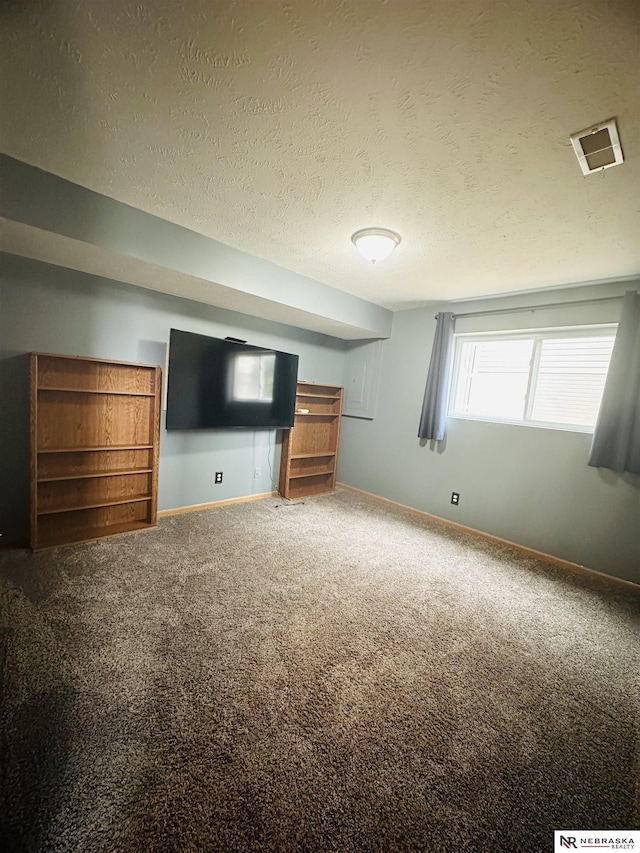 unfurnished living room featuring visible vents, a textured ceiling, baseboards, and carpet floors