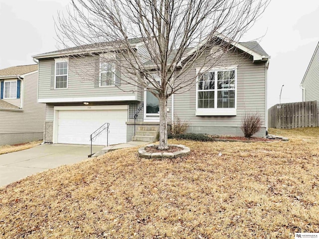 view of front facade with concrete driveway, an attached garage, and fence