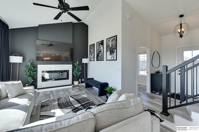 living room with a wealth of natural light, stairway, and ceiling fan with notable chandelier