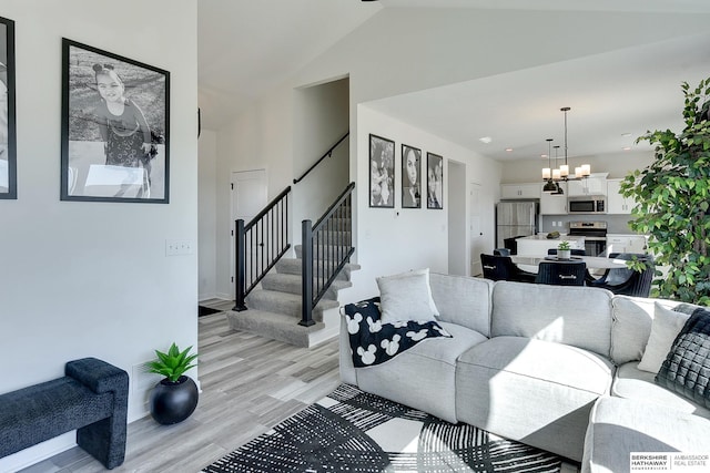 living area featuring baseboards, lofted ceiling, light wood-style flooring, stairs, and a notable chandelier