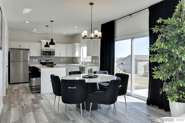 dining area featuring a chandelier, recessed lighting, and light wood finished floors