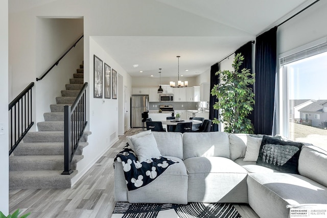 living area featuring stairway, baseboards, visible vents, an inviting chandelier, and light wood-type flooring