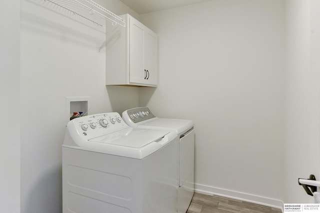 laundry room with baseboards, cabinet space, separate washer and dryer, and light wood-style flooring