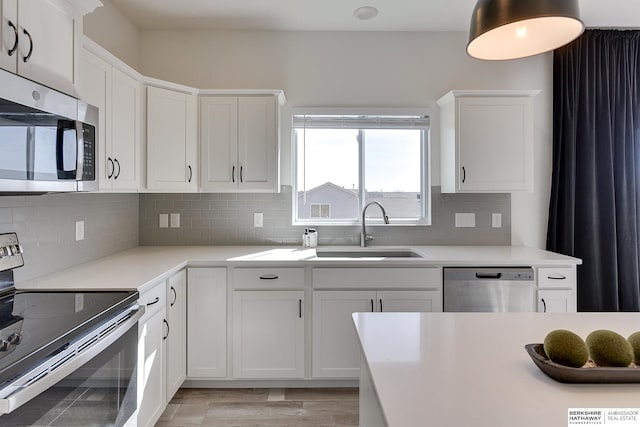 kitchen featuring a sink, decorative backsplash, white cabinets, and stainless steel appliances