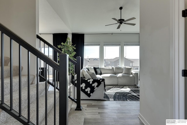 living area with a towering ceiling, stairway, wood finished floors, and a ceiling fan