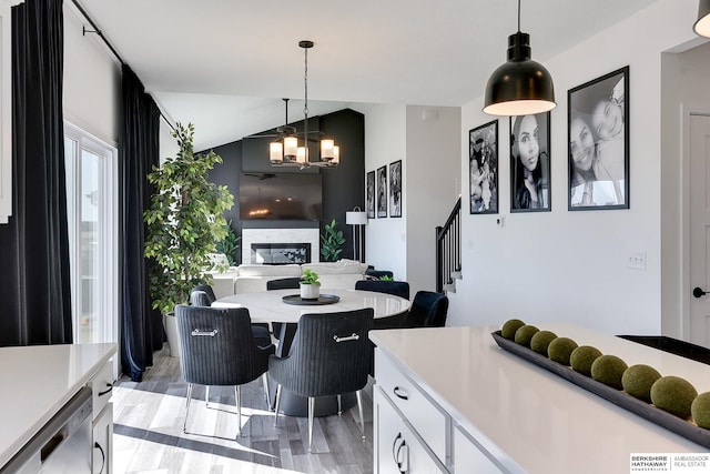 kitchen featuring hanging light fixtures, a glass covered fireplace, light countertops, and stainless steel dishwasher