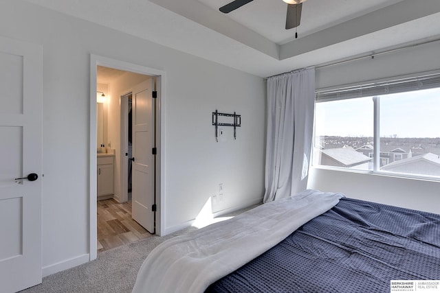 bedroom featuring baseboards, light carpet, connected bathroom, and a ceiling fan