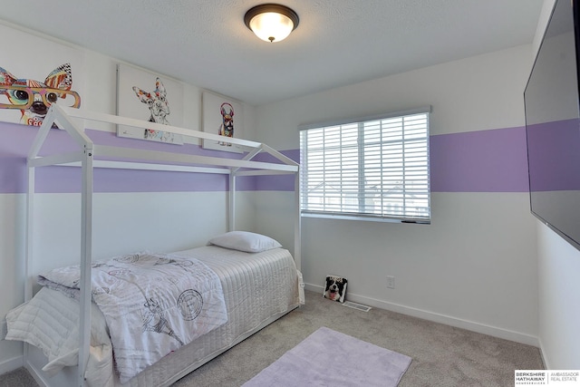 carpeted bedroom featuring a textured ceiling and baseboards