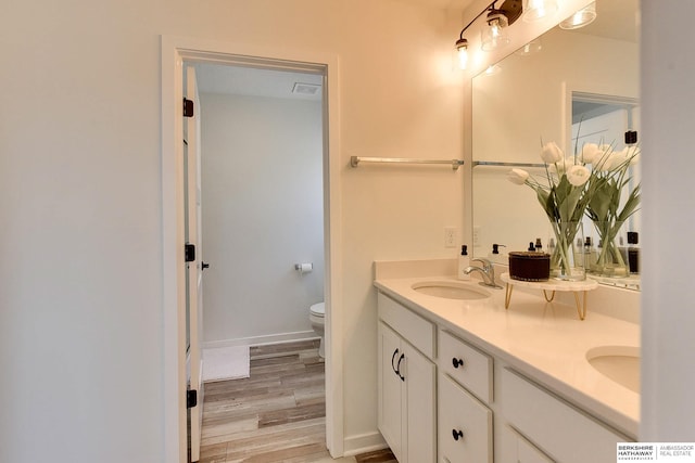 full bathroom with visible vents, toilet, a sink, wood finished floors, and double vanity