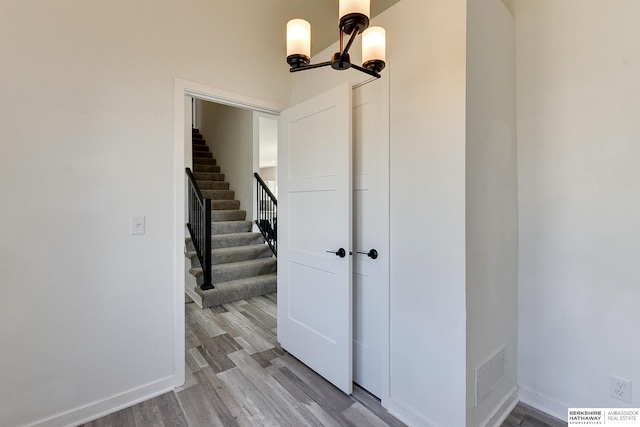 interior space with visible vents, baseboards, an inviting chandelier, and wood finished floors