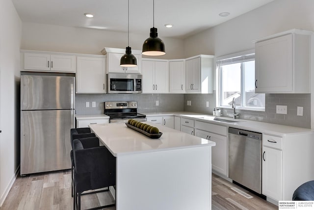 kitchen featuring light wood-type flooring, stainless steel appliances, backsplash, and a sink