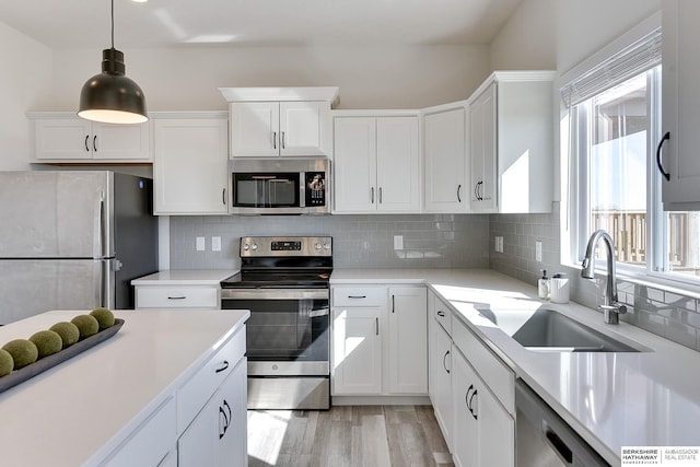 kitchen featuring light countertops, decorative backsplash, stainless steel appliances, white cabinetry, and a sink