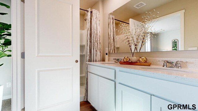 bathroom featuring double vanity, visible vents, curtained shower, and a sink