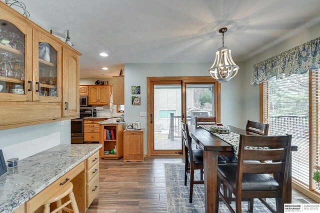 dining space featuring a chandelier, recessed lighting, a textured ceiling, and wood finished floors