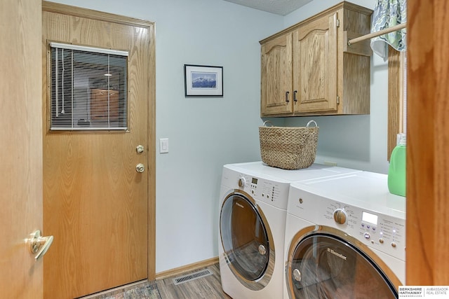 clothes washing area featuring visible vents, light wood finished floors, baseboards, separate washer and dryer, and cabinet space