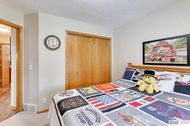 carpeted bedroom featuring baseboards, visible vents, a closet, and a textured ceiling