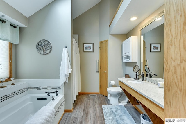 bathroom with vanity, wood finished floors, baseboards, a garden tub, and toilet