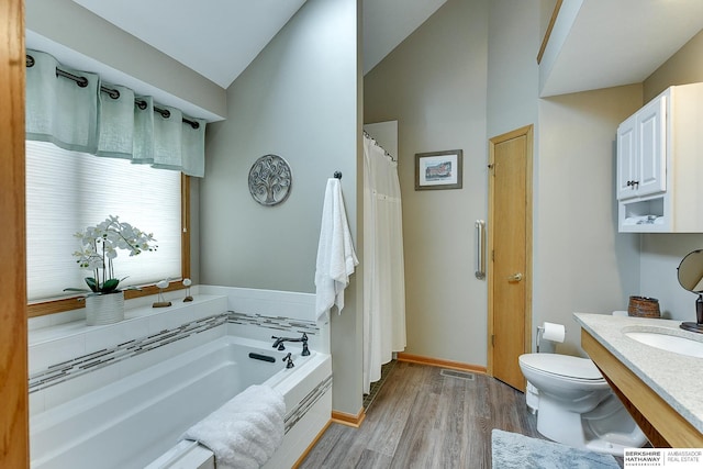 bathroom featuring visible vents, toilet, a garden tub, vaulted ceiling, and wood finished floors