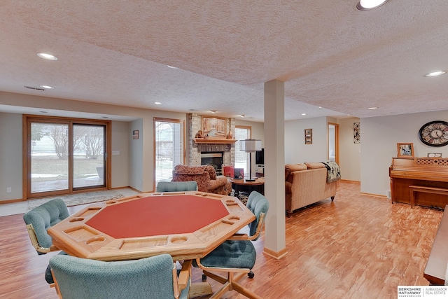 game room with a stone fireplace, recessed lighting, baseboards, and light wood finished floors