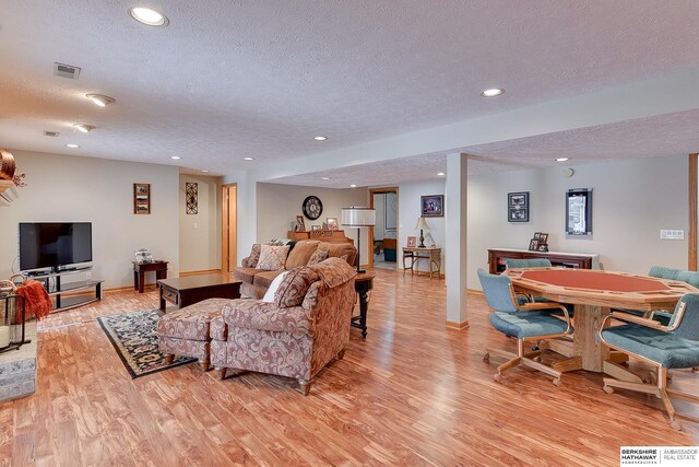 living room with visible vents, a textured ceiling, recessed lighting, light wood-style floors, and baseboards