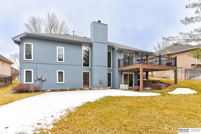 rear view of property featuring a wooden deck, a chimney, a yard, and fence