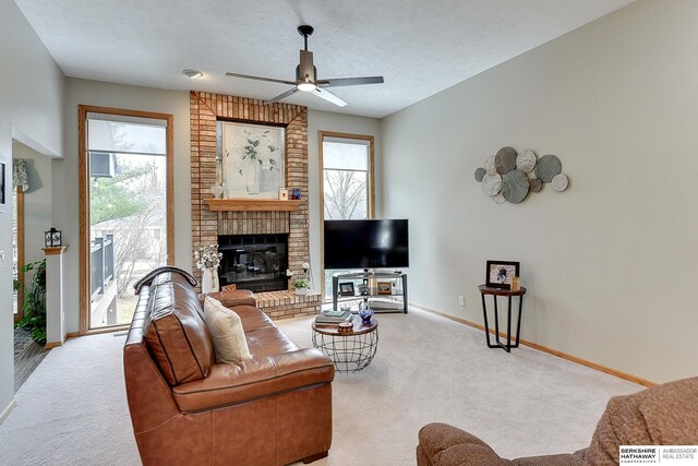 living room featuring a brick fireplace, carpet flooring, baseboards, and plenty of natural light