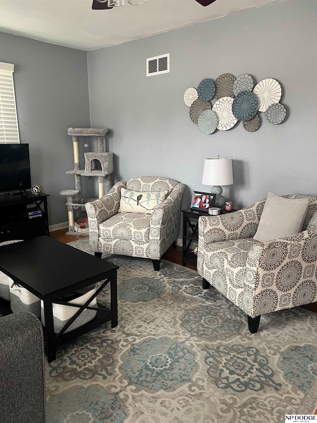 living room with wood finished floors, a ceiling fan, visible vents, and baseboards