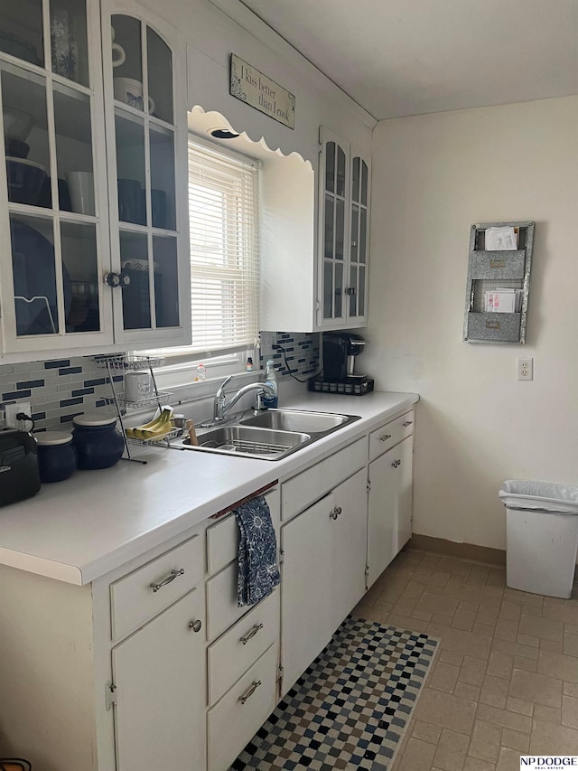 kitchen with a sink, decorative backsplash, white cabinets, and light countertops