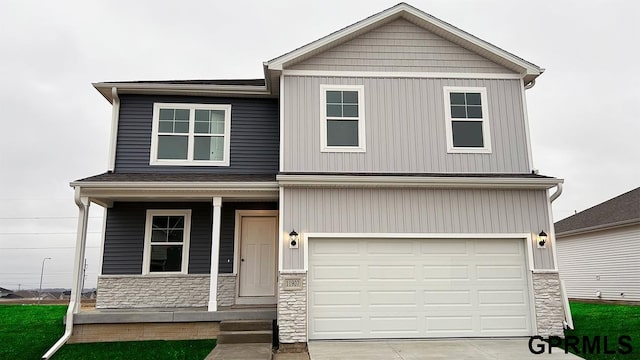 craftsman-style house featuring a garage, stone siding, covered porch, and driveway