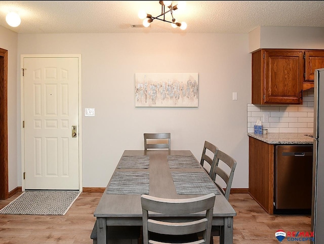 dining area featuring a textured ceiling, light wood-type flooring, and a chandelier