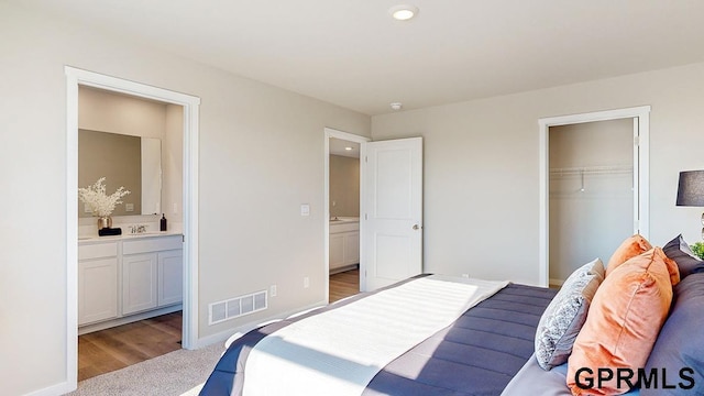 carpeted bedroom featuring visible vents, baseboards, a closet, and ensuite bath