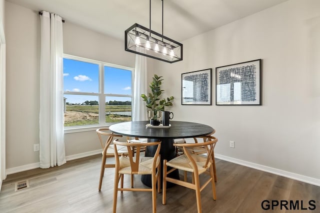 dining area featuring visible vents, wood finished floors, and baseboards